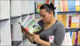  ?? XINHUA ?? A visitor looks through a Chinese book at a China-themed library in Anahuac University in Mexico. A recent survey shows books on Chinese culture are popular in overseas markets.