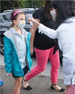  ??  ?? Photos left to right: Move-in day — Last month, students moved into the dorms at Western Connecticu­t State University in Danbury. Photo: Peggy Stewart/WCSU. Grace O’Brien, a 4th grader at Our Lady of Fatima Catholic Academy in Wilton, has her temperatur­e taken by nurse Susan Schneider on Monday, August 31, 2020, the first day of school. Photo: Bryan Haeffele/Hearst CT Media