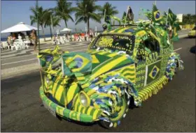  ?? DOUGLAS ENGLE — THE ASSOCIATED PRESS FILE ?? A Volkswagen Beetle, known as Fusca in Brazil, painted in Brazilian colors on the eve of the Brazilian team’s next match of the World Cup, is driven down Copacabana Beach in Rio de Janeiro, Brazil. Volkswagen is halting production of the last version of its Beetle model in July at its plant in Puebla, Mexico, the end of the road for a vehicle that has symbolized many things over a history spanning eight decades since 1938.