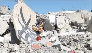  ?? (Photo by MOHAMMED ABED / AFP) ?? Children stand next to a fallen wall bearing a mural amid the rubble of a building destroyed in Israeli bombardmen­t in Rafah in the southern Gaza Strip on February 22, 2024.