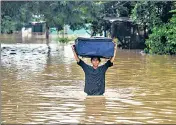  ?? AFP ?? A woman wades through a flooded street in Honduras.