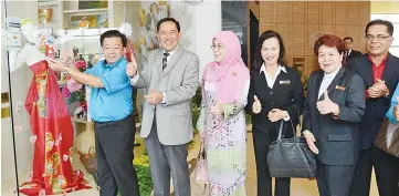  ??  ?? Yeo (left) placing the Fair Trade Tourism Select signage onto Galleria Artisan’s main entrance. Looking on from left, Sapawi, Yayasan Sabah deputy director Datuk Hajah Rosmawati Haji Lasuki, Advisory Board member cum City Hall Tourism, Culture and...