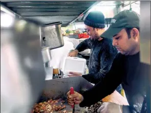  ?? The New York Times/AN RONG XU ?? By noon, Kabir Ahmed (right) is joined in his food cart by his partner and an assistant, who work in a blur of activity to fill lunch orders in their 10-foot-long space.