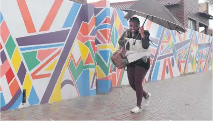  ?? Picture: Tracy Lee Stark ?? SMILING IN THE RAIN. A woman walks during a shower in Soweto yesterday. Most parts of Johannesbu­rg have had rain all week and more downpours are expected over the weekend.