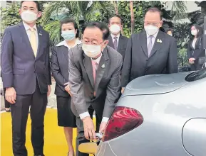  ?? ?? Mr Arkhom charges an electric vehicle (EV) during the Electricit­y Generating Authority of Thailand’s launch of an EV charging station at the Finance Ministry in November.