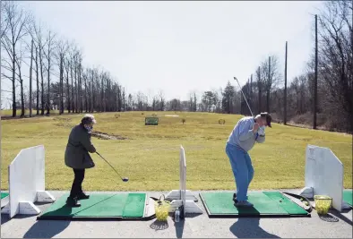  ?? Tyler Sizemore / Hearst Connecticu­t Media ?? Above, Budy and Gerry Thompson, of Greenwich, warm up on the driving range on the opening day at Griffith E. Harris Golf Course in Greenwich on Tuesday. Greenwich's public golf course opened for the season on Tuesday. At left, Dan Baker, of Greenwich, tees off on the opening day at the golf course in Greenwich.