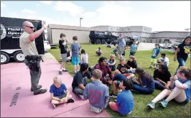  ?? NWA Democrat-Gazette/FLIP PUTTHOFF ?? Deputy Matt Nading talks to youngsters Wednesday during a Police Athletic League event at the Benton County Sheriff’s Office in Bentonvill­e.