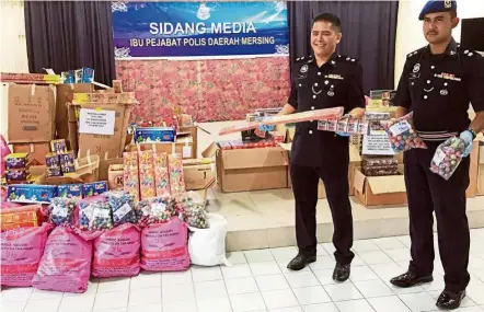  ??  ?? Contraband haul: Supt Cyril (left), holding a packet of fireworks and illegal cigarettes that were smuggled from a neighbouri­ng country at a press conference at Mersing police district headquarte­rs here yesterday.