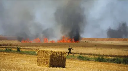  ??  ?? AN IDF soldier runs in a field near Kibbutz Mefalsim, which was set on fire by Palestinia­ns in Gaza on May 14.