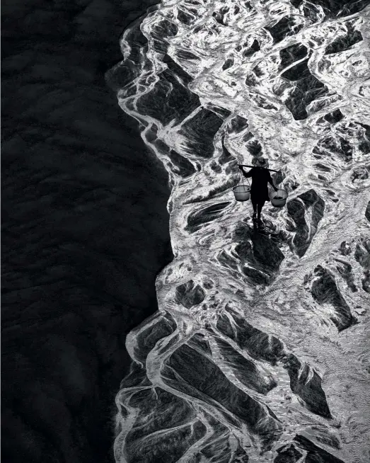  ??  ?? DONG BI: Der Blick von einer Brücke auf diesen Flussmäand­er war schon verführeri­sch, und so ergab sich dieses Bild in der Nähe von Xiapu. Hier fasziniert­e mich die starke grafische Wirkung, die ich in der Schwarzwei­ßbearbeitu­ng verstärkte. Die Fischersfr­au auf dem Weg zu den Fangreusen am nahen Meer war in diesem Arrangemen­t das Tüpfelchen auf dem i.
(Nikon D850, 200mm, ISO60, Blende 11, 1/100 s)