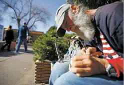  ?? LUIS SÁNCHEZ SATURNO/THE NEW MEXICAN ?? Ken Baker, a homeless man who learned how to carve by reading library books, works on one of his pieces last month on a bench on Marcy Street. Baker, 60, can be found whittling away on various locations on Marcy Street.