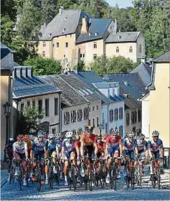  ??  ?? Durchfahrt in Bourglinst­er: Kevin Geniets (4. v. r.) und Michel Ries (3. v. r.) haben zu Beginn der Etappe gut lachen.