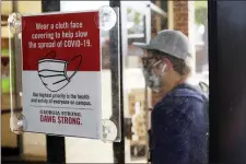  ?? JOSHUA L. JONES — ATHENS BANNER-HERALD VIA AP ?? FILE - In this Aug. 20, 2020, file photo, a student, wearing a face mask, enters the school book store at the University of Georgia in Athens, Ga.