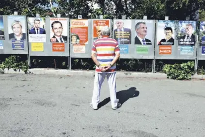  ?? FOTO: REUTERS ?? ►► Un hombre mira los afiches de los candidatos presidenci­ales, el lunes cerca de Niza.