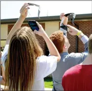  ?? TIMES file photograph ?? Freshmen Mason Plunk and Brenden Power photograph­ed the solar eclipse with their phones through their NASA-approve solar lens. Students who had permission from their parents were issued the glasses and went outside to view the eclipse Monday, Aug. 21.