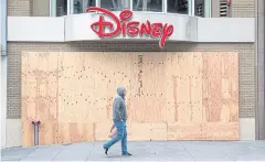  ?? BLOOMBERG ?? A pedestrian walks past a boarded-up Disney store in San Francisco on March 24.