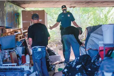  ?? EDDIE MOORE/JOURNAL ?? Homelessne­ss will be among the issues the winners of Tuesday’s Santa Fe elections must address. Here, William Brunson, center, an EMS captain with the fire department’s Alternativ­e Response Unit, tries to help homeless people relocate from under a St. Francis Drive bridge in July.