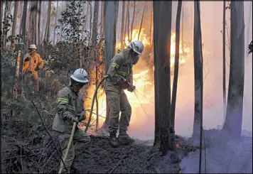  ?? ARMANDO FRANCA / ASSOCIATED PRESS ?? Firefighte­rs from the Portuguese National Republican Guard work to stop a forest fire from reaching the village of Avelar on Sunday morning. Many victims were trapped in their cars as flames swept over a road Saturday night.