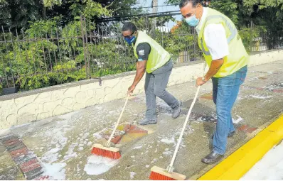  ??  ?? Mayor of Montego Bay Homer Davis (right) and Member of Parliament for Central St James Heroy Clarke scrub a sidewalk along St James Street, during a sanitisati­on exercise in Montego Bay on Sunday, June 28.