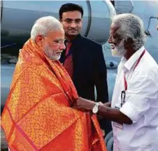  ??  ?? Modi is received by the president of the BJP in Kerala K. Rajashegar­an at the Kozhikode airport yesterday.