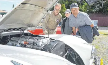  ?? FOTOS: BERND BAUR ?? Tom Douglas (links) lässt Dominik und Christian Ruf unter die Motorhaube seines Jaguar XK 120 OTS, Baujahr 1952, blicken. Der offene Zweisitzer wird von einem Sechszylin­der-Flugzeugmo­tor mit 186 PS angetriebe­n.