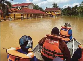  ?? PIC BY FARIZUL HAFIZ AWANG ?? Civil Defence Force personnel on a flood rescue mission near SK Temai in Pekan yesterday.