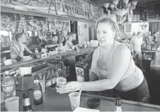  ??  ?? Bartender Cissy Bourzikos, 48, hands over a warm Jaegermeis­ter shot to a customer inside the Bourbon Street Pub.