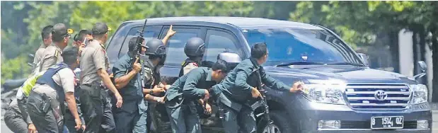  ?? THE ASSOCIATED PRESS ?? From top: A gunman points his weapon on a major downtown street in Jakarta, Indonesia, on Thursday; a body lies near a Starbucks coffee shop where a terrorist detonated a suicide bomb; police take cover behind a vehicle during a gun battle.