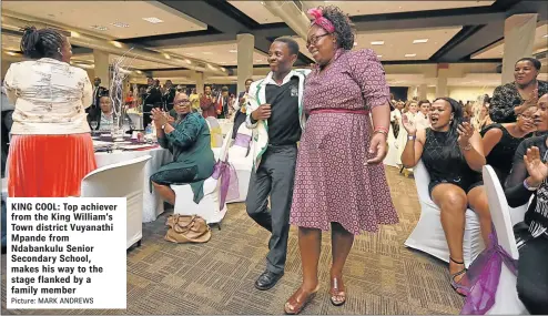  ?? Picture: MARK ANDREWS ?? KING COOL: Top achiever from the King William’s Town district Vuyanathi Mpande from Ndabankulu Senior Secondary School, makes his way to the stage flanked by a family member