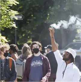  ??  ?? SMOKY STATEMENT: A Black Lives Matter protester releases smoke prior to the march.