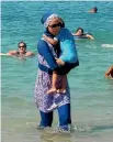  ?? PHOTO: REUTERS ?? A woman wearing a burkini walks in the water on a beach in Marseille, France, the day after the country’s highest administra­tive court suspended a ban on full-body burkini swimsuits.