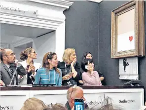  ??  ?? Going, going: spectators look on in disbelief as the Girl with Balloon painting begins to shred at Sotheby’s