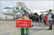  ?? XINHUA ?? A young passenger holds a celebrator­y placard in front of the domestic large passenger aircraft C919 at Shanghai Hongqiao Airport on Friday. This is the first time that the C919 is being used during the Spring Festival travel rush.