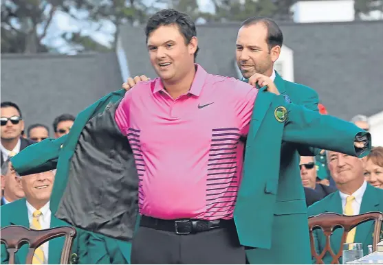  ?? Picture: Getty Images. ?? Reed all about it – The new Masters champion is presented with his green jacket by Sergio Garcia of Spain.