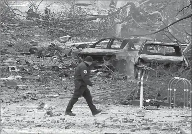  ?? Associated Press photo ?? A law enforcemen­t member walks past damage from an explosion in downtown Nashville, Tenn., Friday. Buildings shook in the immediate area and beyond after a loud boom was heard early Christmas morning.