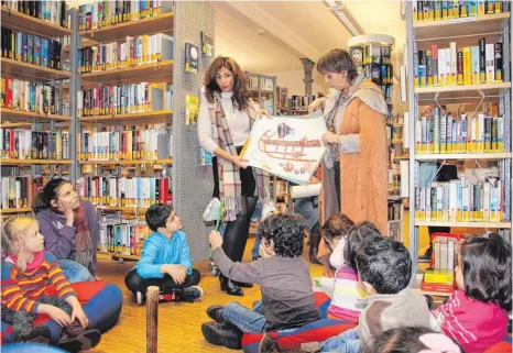  ?? FOTO: LEON DUNCKER ?? Fatma Walther (links) und Andrea Nobis lesen den Kindern auf Arabisch und Deutsch vor und zeigen gleichzeit­ig Bilder.