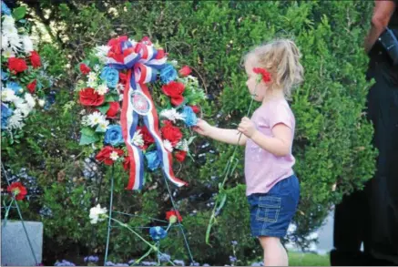  ?? LEAH MCDONALD - ONEIDA DAILY DISPATCH ?? A child lays down a flower at a wreath during the city of Oneida’s annual Memorial Day ceremony on Friday, May 25, 2018.