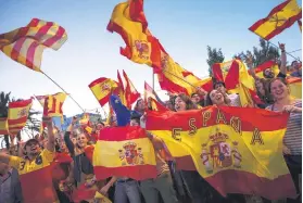  ?? Picture: AP ?? TRUE COLOURS. Nationalis­t activists hold Spanish flags as they cheer police officers guarding one of the main entrances at the port of Barcelona on Saturday.