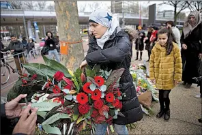  ?? AP/PETER DEJONG ?? Women representi­ng the Muslim community in Utrecht, Netherland­s, places a wreath Tuesday at a makeshift memorial for victims of Monday’s tram shooting.