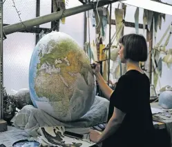  ?? KIN CHEUNG/THE ASSOCIATED PRESS ?? An artist paints a globe in February at Peter Bellerby’s studio in London.