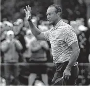  ?? Robert F. Bukaty / Associated Press ?? Tiger Woods waves to the gallery after putting out on No. 18. Woods made the cut and is at 1-over 145.