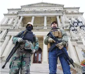  ?? AP FILE PHOTO/PAUL SANCYA ?? Armed men stand on the steps at the State Capitol after a rally in support of President Donald Trump in Lansing, Mich.