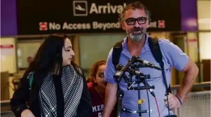  ?? BARRY CHIN/GLOBE STAFF ?? Hazem Shafai and his wife Sanaa talked with reporters Tuesday at Logan Airport after they arrived after more than a month in Gaza.