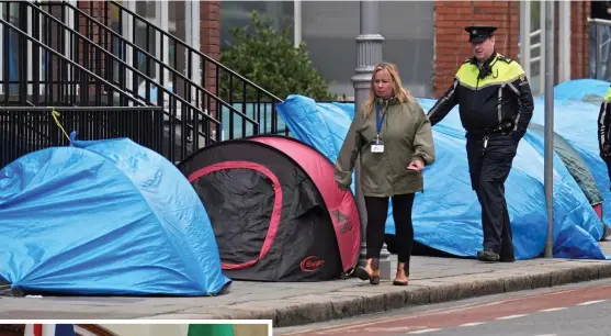  ?? ?? Tent city: Police and members of the public yesterday walk past the growing number of shelters put up by asylum seekers on the streets of Dublin