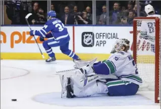  ?? RICK MADONIK, TORONTO STAR ?? As Maple Leafs centre Auston Matthews celebrates his third-period goal, Vancouver Canucks goaltender Jacob Markstrom looks for the replay. The Leafs won, 3-2 in a shootout. Matthews also got on of the shootout goals.