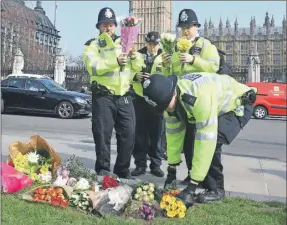  ??  ?? Policías colocan flores en un altar improvisad­o ante el Parlamento, donde ocurrió un ataque en Londres