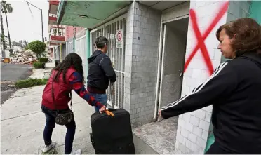  ??  ?? People walking with a roller bag past a building marked with an X, which indicates that it will be demolished, after the earthquake in Mexico City. — Reuters Major damage: