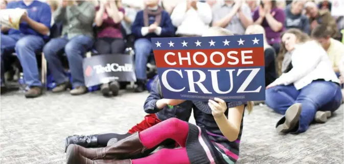  ??  ?? IOWA: A young girl holds up a campaign sign as people applaud during a campaign event featuring Republican presidenti­al candidate, Sen Ted Cruz, R-Texas, at Western Iowa Tech Community College in Sioux City. — AP