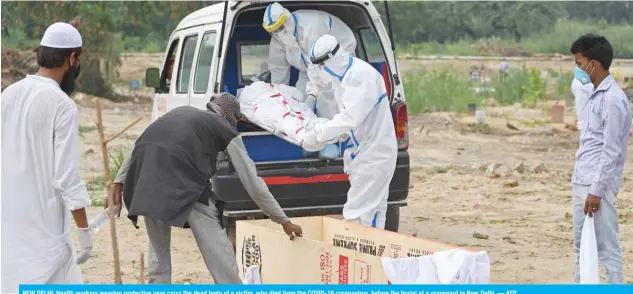  ??  ?? NEW DELHI: Health workers wearing protective gear carry the dead body of a victim, who died from the COVID-19 coronaviru­s, before the burial at a graveyard in New Delhi. — AFP