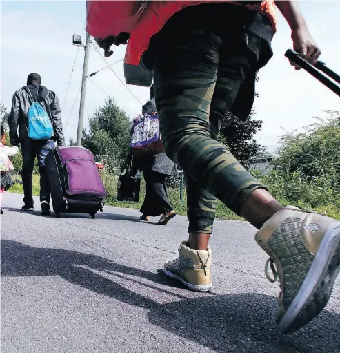  ?? CHARLES KRUPA / THE ASSOCIATED PRESS FILES ?? A family from Congo approaches an unofficial U. S.- Canada border crossing in Quebec last August. The RCMP are intercepti­ng roughly 2,000 people a month who are crossing into the province between ports of entry.